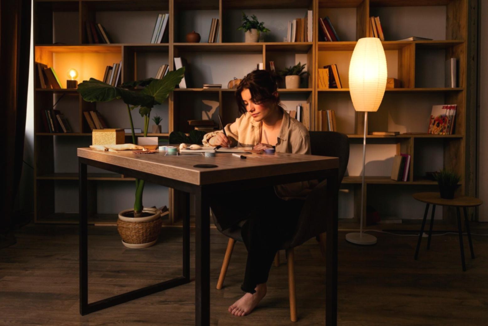 Person arbeitet konzentriert am Laptop mit Dokumenten und Notizen